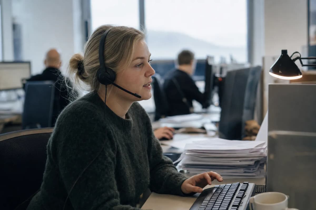 Medarbejder i et åbent kontorlandskab med headset på