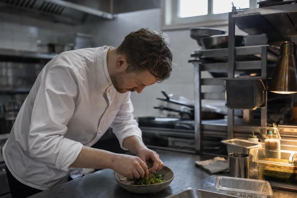 Kokk ved en benk på et restaurantkjøkken før servering