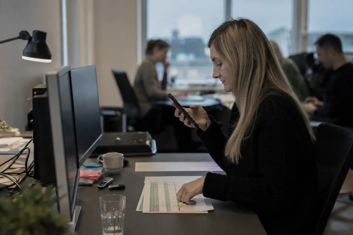 Konsulent ved et bord med to skærme og en telefon i hånden