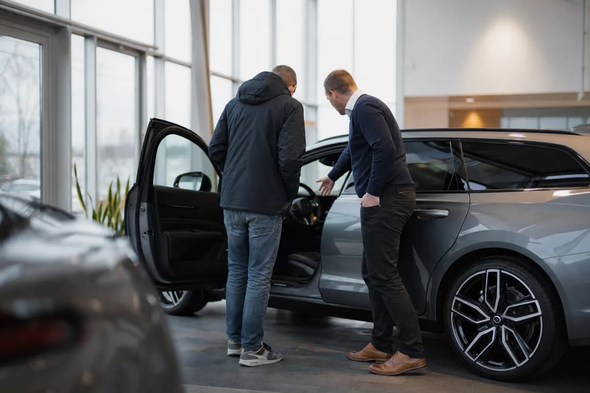 Sælger og kunde ved en bil i et lyst udstillingslokale