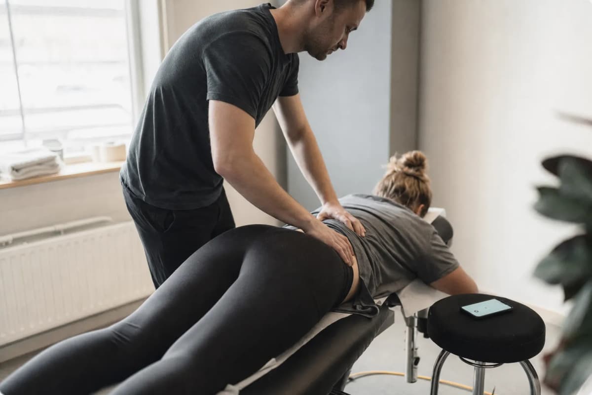 Fysioterapeut behandlar en patient på en brits medan telefonen lyser obesvarad bredvid