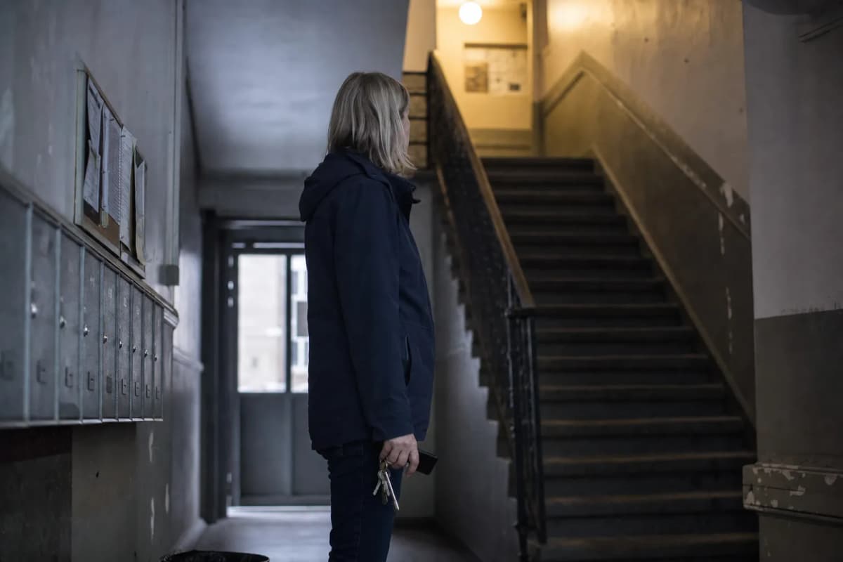 Administrator i opgangen til en ejendom med nøgler og en mobil i hånden