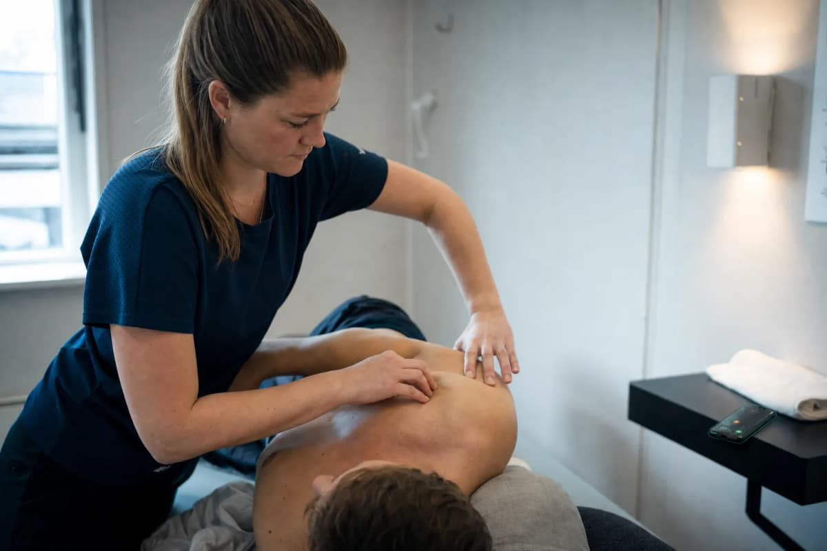 Fysioterapeut behandler en patient på en briks i et lyst behandlingsrum