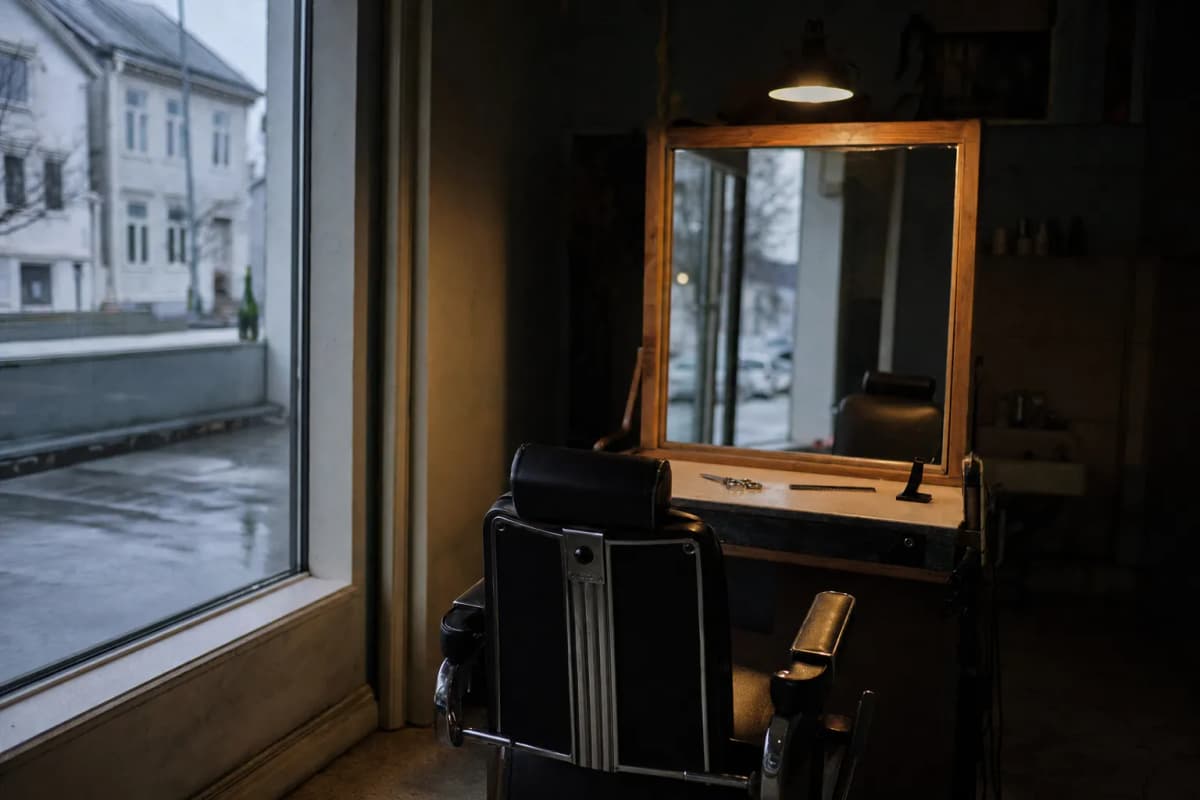 Frisørstol foran et spejl i en tom salon tidligt på dagen