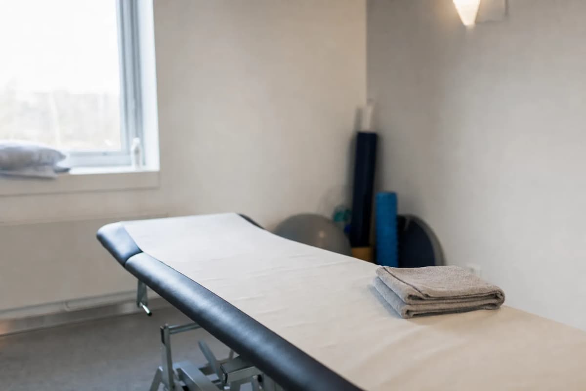 Behandlingsbriks med rent lagen i et lyst behandlingsrum