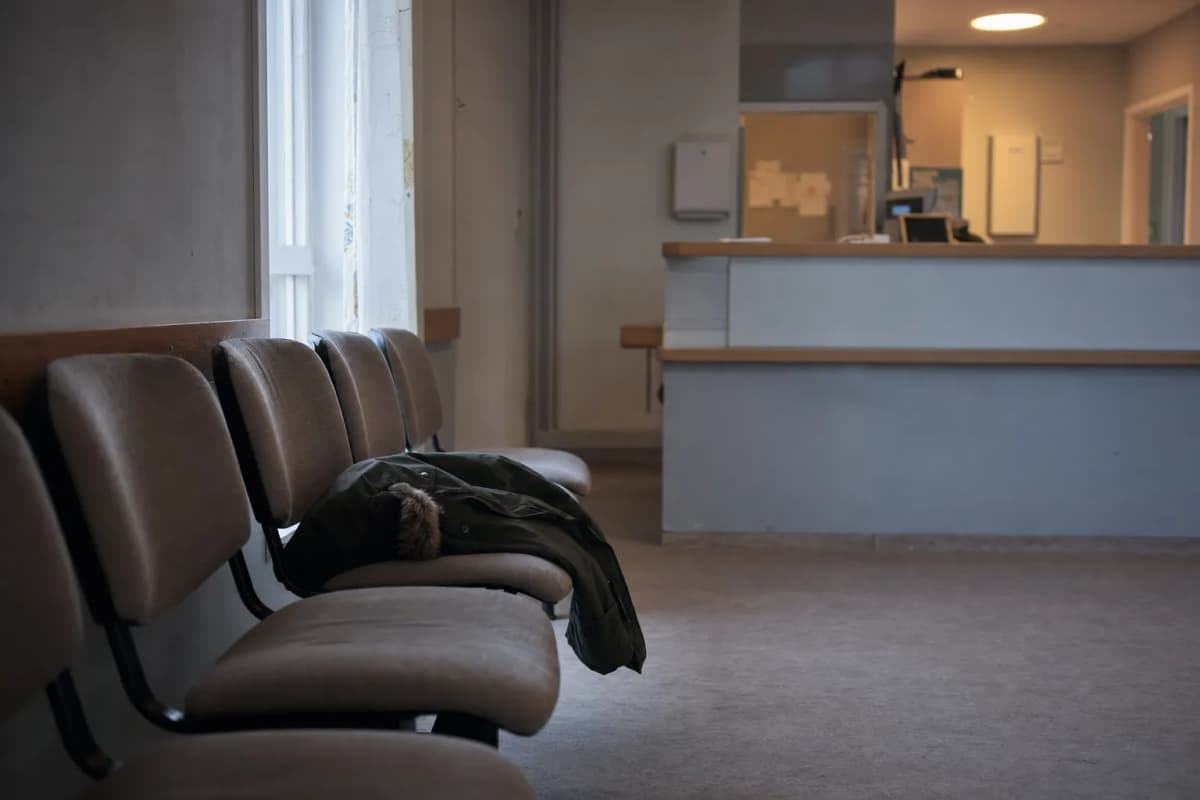 Venteværelse på en klinik med tomme stole og en receptionsskranke