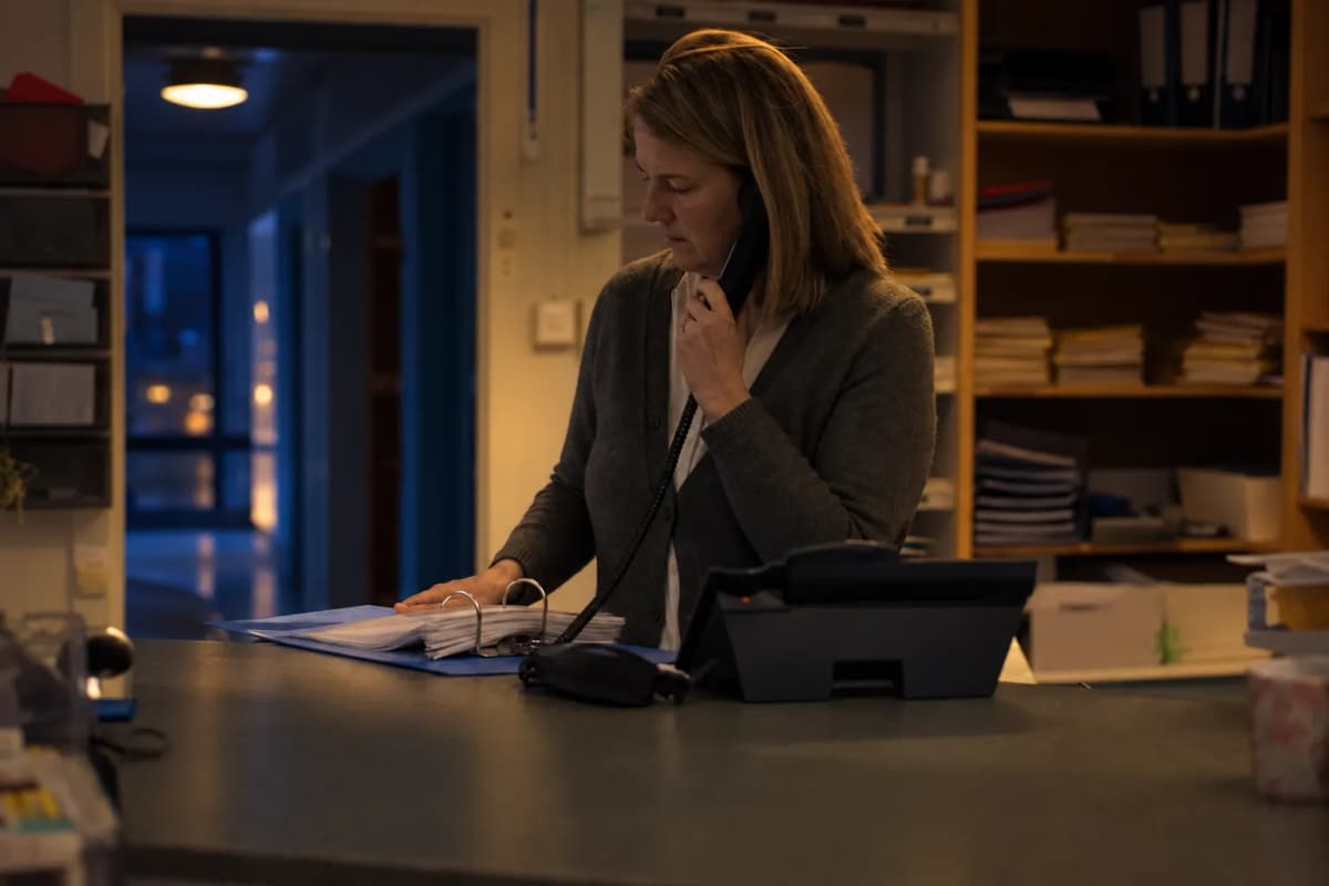 Anställd på en skolexpedition vid en disk med en telefon och en pärm